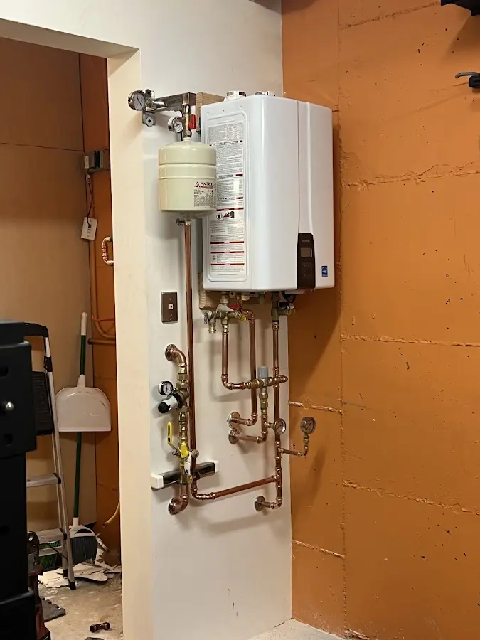 Plumbing technician inspecting water heater connections in Blendon